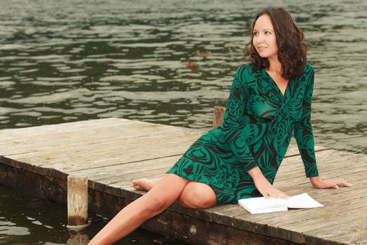 Attractive woman is recovering at the lake while reading