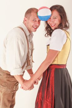 Bavarian couple in love laughing when playing with a ball