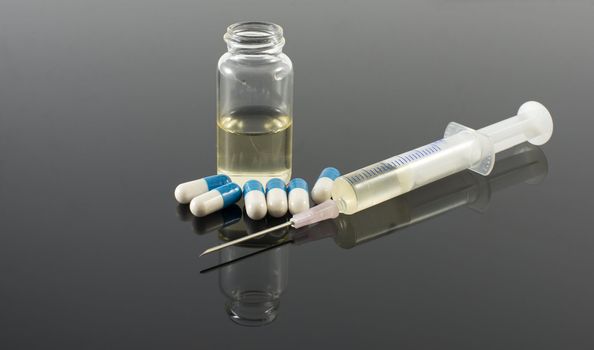 injectionn needle pills and bottle on dark background