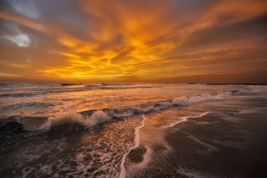 The setting sun behind the clouds on the sea of orange colors everything