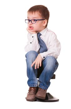 Angry kid in shirt and jeans sits on small chair, on white background