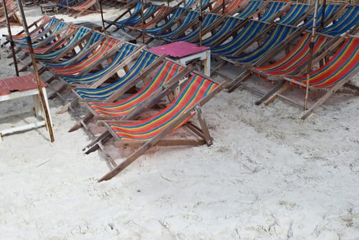 Wooden beach chairs under umbrella, taken on a sunny day