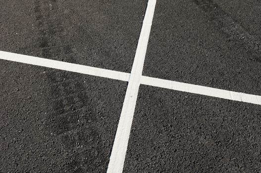 Detail of tire marks and white stripes painted on the road