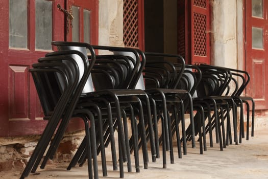 Many black metal chairs stacked on an old building