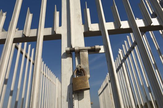 Iron gate padlocked against the blue sky