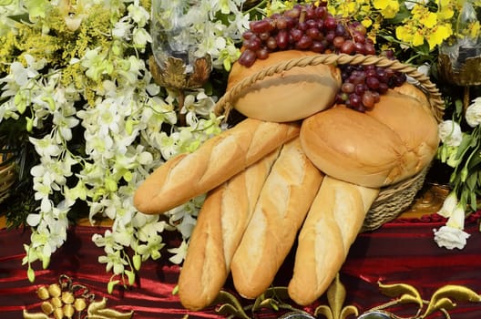 Bread, flowers, and grapes still life on red cloth