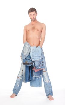 Cool shirtless trendy man in a pair of modern ragged jeans standing deciding what to wear with two pairs of denims in his hands