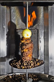 Mixed meat on a vertical spit with whole onion on top