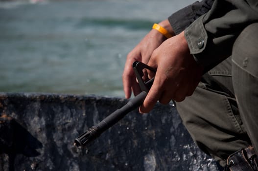 gun in hand of asian soldier in boat