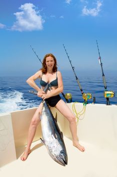 beautiful bikini fisher woman holding big bluefin tuna catch on boat deck