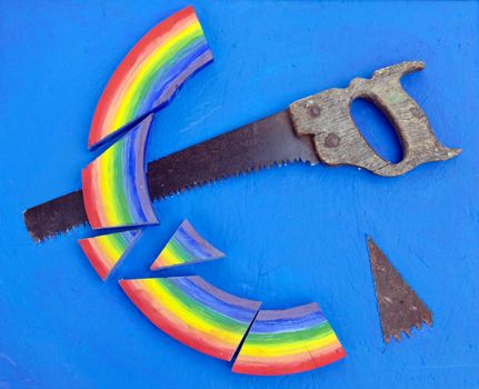 Concept rainbow cut with retro hand saw on blue background.