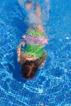 children gilr swimming underwater in blue tiles pool