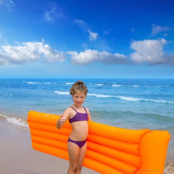 children kid girl standing in beach shore with orange floating lounge ok hand sign
