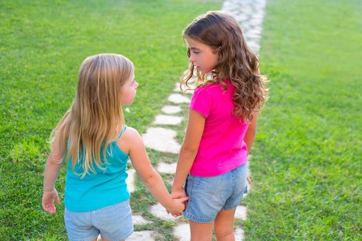 friends sister girls together in grass garden track holding hand looking eachother