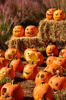 Jack-o-lanterns sit on haystacks displayed for Halloween