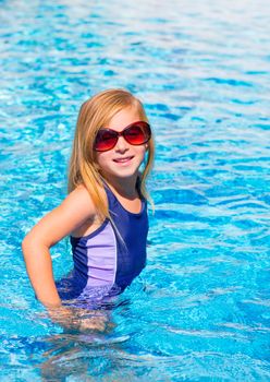 blond kid girl in blue pool posing with sunglasses smiling