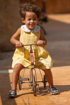 Happy girl riding a centenarian toy tricycle