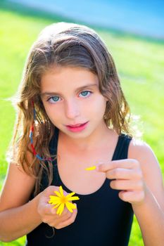 blue eyes children girl testing love with yellow daisy flower petals