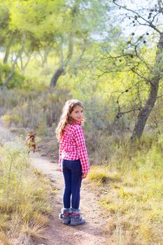 children girl walking in the pine forest with doggy around