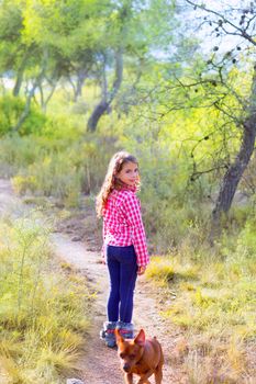 children girl walking in the pine forest with doggy around