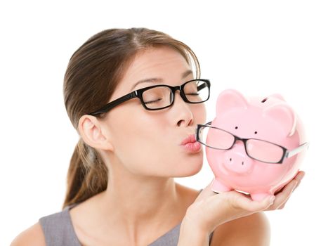 Glasses sale concept. Happy woman kissing piggy bank wearing eyewear glasses. Mixed race Asian Chinese / Caucasian female model isolated on white background.