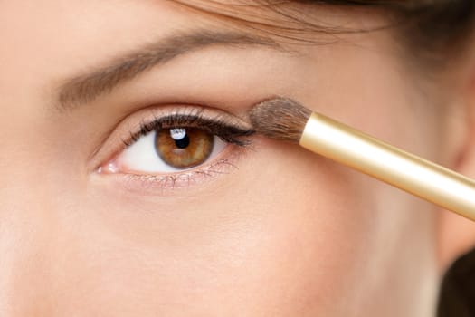 Eye makeup woman applying eyeshadow powder. Woman putting shadow powder on eyes with makeup brush. Closeup of eyelid and eyebrow.