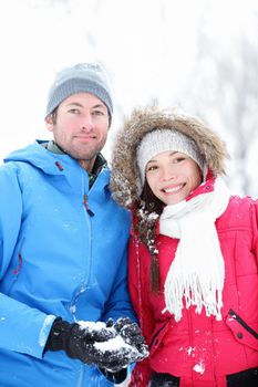 Couple in winter portrait. Young interracial couple smiling looking at camera outside in snow winter forest.