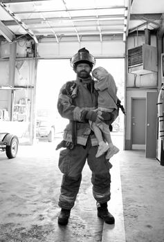 A firefighter holding his daughter in black and white