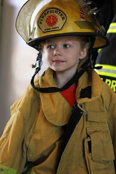 A young girl wearing a firefighter's gear