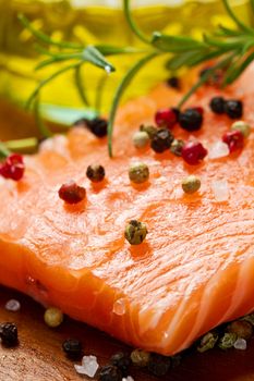 Fresh salmon fillet on wooden board with pepper and rosemary