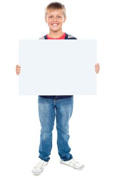 Full length portrait of boy holding blank whiteboard. Dressed in casuals