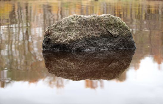 a huge boulder reflected in the water