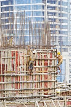 MUMBAI, INDIA - OCTOBER 8, 2011: Elevated vantage point of urban landscape of builders working on the edge of a 17th floor building without a safety harness and wearing open toe flip flops.