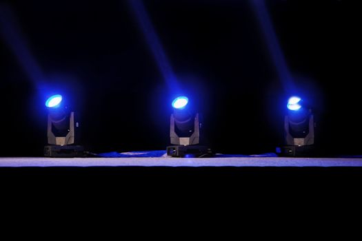 Horizontal capture of blue spot lights on a theater stage pre-curtain raise. Location of shot Goa, India