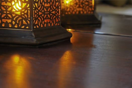 Amber colored bulb in a oriental eastern design table casts beams over table surface and reflections in mirror