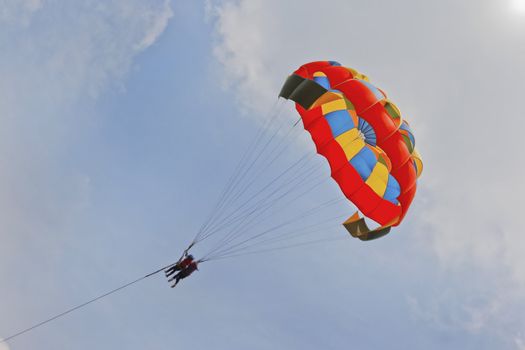 Generic landscape of a pair of female paragliders sailing amongst blue skies and clouds. Location could have been any where but this shot is take in Pachmarhi, Madhya Pradesh, India