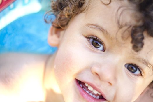 beautiful blond boy with curls at the pool