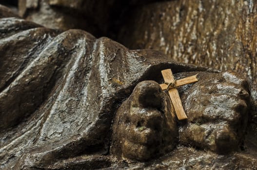 A cross resting on the feet of a statue of Jesus.