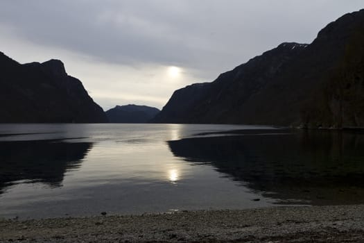 evening view over fjord in norway with cloudy sky and steep coast