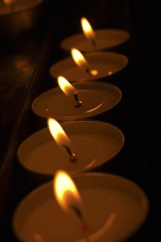 A group of warm glowing candles on black background
