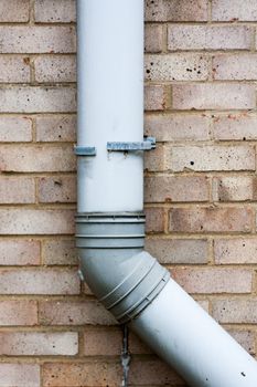 Brown brick wall with grey gutter or drain pipe.