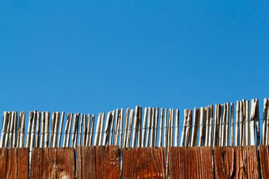 reed fence against blue sky with space for text