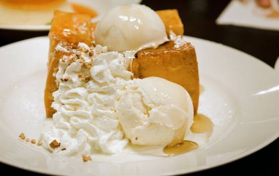 toast with ice cream ,whipping cream and honey syrup on white plate