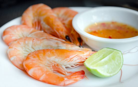 Boiled shrimps on plate served with spicy sauce and lemon