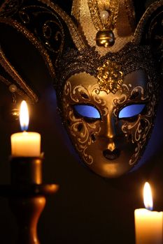 Lighting candles against beautiful classical venetian mask on dark background