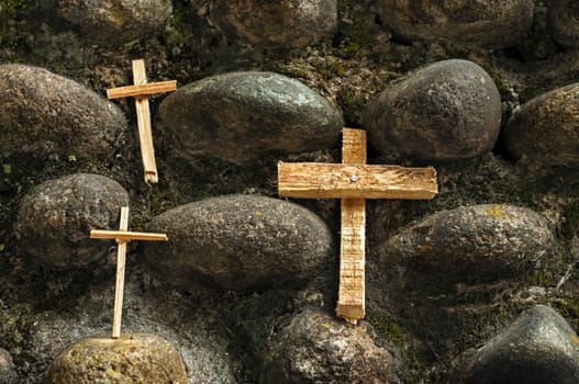 Three wood crosses on a stone wall.