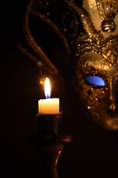 Lighting candle against beautiful classical venetian mask on dark background