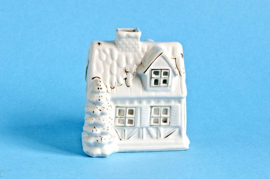 white ceramics christmas house symbol on azure background