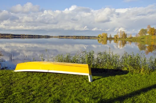 beautiful autumn landscape with yellow boat on coast
