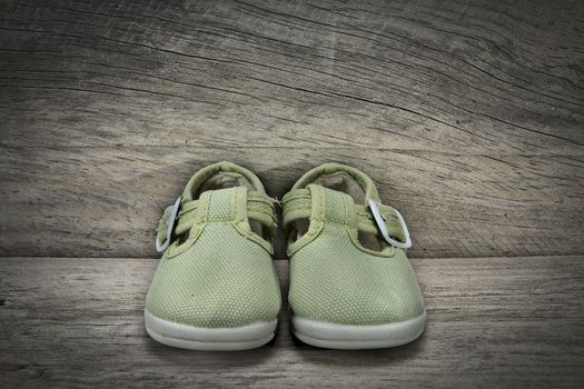 Green shoes for baby on an old wooden shelf